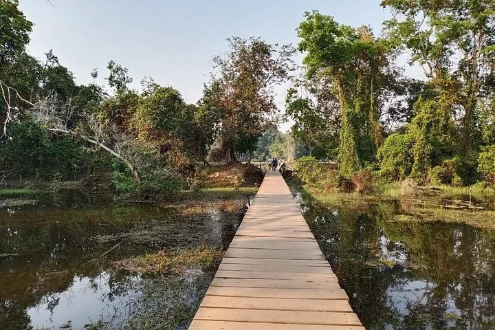 Hölzerner Steg über dem Wasser, der zu Bäumen bei Neak Pean führt